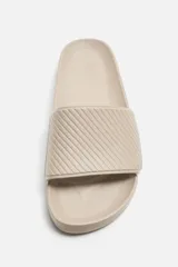 Chancla tipo pala monocolor negra, con suela de goma y tira ancha en el empeine con relieve acanalado.