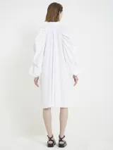 Vestido camisero blanco con botones frontales, cuello camisero, manga larga abullonada con puños ajustables y corte a la rodilla.