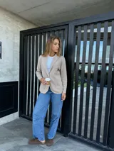 Blazer color beige de algodón con solapas y parche bordado en el pecho.