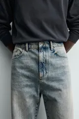 Jeans de corte recto y tiro medio confeccionados en denim de algodón con efecto lavado, diseño de cinco bolsillos y cierre frontal con cremallera y botón.