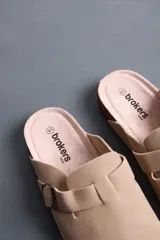 Sandalias cerradas tipo zueco color beige, con tira ajustable y hebilla metálica dorada. Plantilla anatómica y suela de corcho con base de goma.