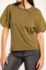 Remera de algodón peinado color negro, con mangas cortas de broderie con diseño calado y terminación festoneada. Presenta un corte oversize y cuello redondo.