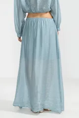 Falda larga hasta el tobillo color celeste, confeccionada en tejido arrugado liviano con cintura elástica.
