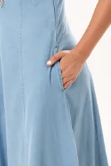 Vestido largo de denim fino y liviano, color celeste, con breteles finos, escote delicado, silueta entallada en la parte superior, falda amplia con recortes verticales y bolsillos laterales.