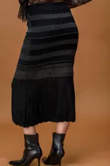Falda midi de tejido de punto en color negro, con diseño de franjas horizontales que combinan diferentes texturas y sutiles detalles de lurex. La parte inferior presenta un tejido más liviano y fluido.