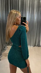 Vestido corto verde brillante con un hombro descubierto y una manga larga abullonada. Presenta un corte en la cintura y fruncido ajustable con cordón en un lateral de la falda.