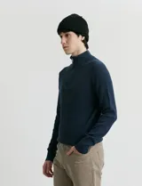 Cardigan de punto color azul marino, con cuello alto y cierre frontal parcial. Presenta diseño de punto inglés en cuerpo y mangas, con terminaciones en punto canalé en cuello y puños.