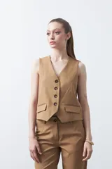 Chaleco sastrero color marrón oscuro, con escote en V, cierre frontal de botones y pinzas de entalle.