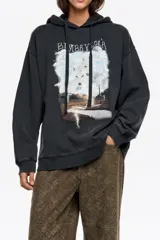 Hoodie de algodón color negro con efecto lavado, corte oversize y capucha con cordones ajustables. Presenta un estampado gráfico frontal con paisaje, lobos y rayos, junto con el logo de la marca.