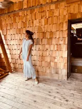 Vestido tejido color gris con hilado levemente brillante, corte oversized y flecos en el ruedo.