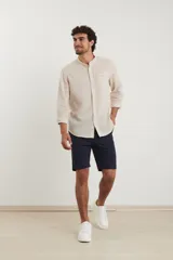 Camisa de cuello mao y manga larga, confeccionada en una mezcla de lino y algodón. Presenta un diseño de corte recto con botones en tono natural y un bolsillo pequeño en el pecho.