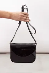 Bandolera compacta de cuero vacuno color gris con efecto gastado, solapa redondeada y correa ajustable.