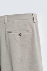 Pantalón de vestir slim fit en color beige, confeccionado en tejido con lana. Presenta cierre frontal con cremallera y botón, bolsillos laterales y bolsillos traseros de doble vivo con botón.