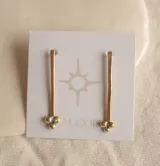 Aros colgantes dorados con tres bolitas plateadas en la base.