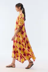 Kaftan maxi amplio de color amarillo, con escote redondo, mangas cortas y ruedo irregular. Presenta un diseño estampado a cuadros con efecto teñido.