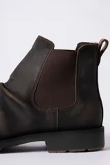 Bota tipo Chelsea de cuero color marrón oscuro con efecto desgastado, paneles laterales elásticos y suela de goma antideslizante.