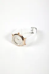 Reloj analógico con caja circular de metal en tono oro rosa y malla de silicona blanca. La esfera presenta un diseño minimalista con marcadores de hora tipo cristal.