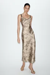 Vestido midi de estilo lencero con estampado animal print, confeccionado en tejido satinado. Presenta escote en pico tanto en el delantero como en la espalda y cuenta con doble tirante fino en color negro.