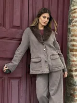 Chaqueta de denim color marrón con efecto lavado, corte recto y cuello con solapa de piel sintética en tono oscuro. Presenta cierre frontal con botones metálicos y dos bolsillos delanteros con solapa.
