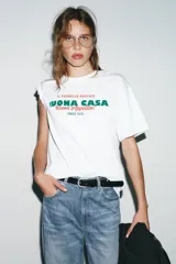Camiseta blanca de manga corta y cuello redondo con estampado frontal en verde y rojo que dice "IL FORNELLO RUSTICO BUONA CASA Buon Appetito! - SINCE 1975 -".