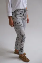 Pantalón de corte recto con cintura elástica y cordón ajustable, confeccionado en tela con estampado floral en tonos grises y blancos sobre base celeste.