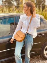 Bandolera pequeña de cuero color marrón claro, con correa larga ajustable y cierre con solapa.