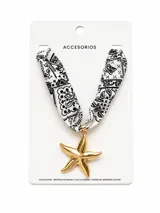 Collar corto con cinta de tela estampada en blanco y negro con patrón Paisley y un gran dije colgante en forma de estrella de mar dorada.