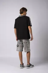 Remera tipo chomba tejida de algodón color negro, con cuello en V y mangas cortas. Presenta detalles de rayas blancas en cuello y mangas, y estampados con logos en el frente.