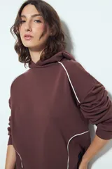 Canguro negro de silueta amplia con capucha integrada y detalles de líneas blancas que recorren el frente y las mangas.