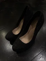 Zapatos de tacón alto tipo plataforma, color negro, completamente cubiertos de pedrería brillante. Presentan un taco grueso y una plataforma delantera que aporta altura y estabilidad.