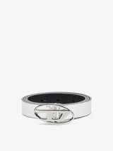 Cinturón reversible de cuero y material sintético. Un lado es blanco brillante y el otro negro. Cuenta con una hebilla metálica plateada con forma de óvalo y el logo 'D' de Diesel en el centro.