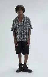 Camisa de manga corta, tejida de punto abierto (símil crochet), con estampado paisley en blanco y negro, y calce oversize.