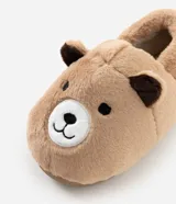 Pantufla cerrada de peluche color tostado con diseño de cara de oso en la parte frontal y orejas pequeñas. Cuenta con suela de goma antideslizante y forro interior suave.