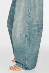 Jeans de tiro medio y corte balloon color azul, con trabillas, bolsillos delanteros y traseros, y cierre frontal con cremallera y botón metálico.