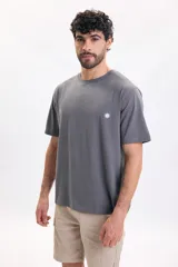 Remera gris oscuro de manga corta, con estampa tipográfica grande en la espalda con el texto 'Tropical Sunsets & Peaceful Waves'.