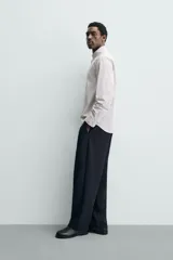 Camisa de corte regular fit confeccionada en tejido de algodón con estampado de cuadros pequeños. Presenta cuello abotonado, manga larga con puños abotonados, bolsillo de plastrón en el pecho y cierre frontal con botones.