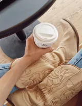 Botas de cuero color marrón y blanco con bordados negros, de estilo cowboy con taco bajo.