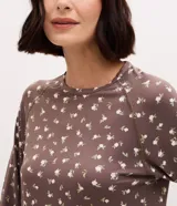 Blusa de pijama marrón con estampado de flores pequeñas, cuello redondo y mangas largas con puños ajustados.