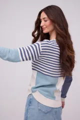 Buzo tejido de algodón con diseño combinado de rayas, bloques de color en tonos beige, celeste y azul, cuello redondo y manga larga.