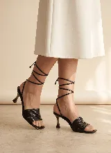 Sandalia de cuero tostado con múltiples tiras finas en la parte delantera, punta cuadrada y taco medio de diseño acampanado. Cuenta con cordones largos para atar alrededor del tobillo.