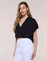 Blusa crop cruzada Allie Rose de tela liviana negra con estampado de lunares blancos, escote en V y cuello camisero.