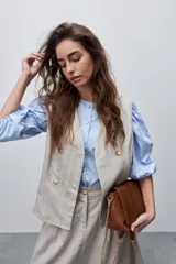 Chaleco de calce entallado color beige, de estilo cruzado con doble botonadura y escote redondo.