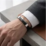 Pulsera de diseño moderno compuesta por una banda de goma negra con detalles metálicos en acero inoxidable y tres apliques circulares decorativos.