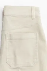 Pantalón de tiro alto confeccionado en pana de algodón, con diseño acampanado, bolsillos de parche frontales y pliegues marcados en el frente y la espalda.