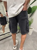Bermuda de jean color negro gastado, corte holgado, con bolsillos cargo laterales.