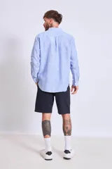 Camisa de corte regular con diseño de rayas verticales finas en tonos claros, cuello clásico y mangas largas con puños abotonados.