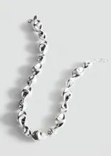 Collar de metal plateado con diseño de cuentas de formas orgánicas y abstractas, con cadena de ajuste y cierre de mosquetón.