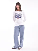 Remera negra de manga larga con escote en V y estampa frontal blanca con diseño de soles y la frase 'Woke Up'.