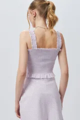 Crop top cuadrillé sin mangas con volados en la cintura.