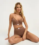 Soutien top femenino color marrón, confeccionado en poliamida sin costuras, con escote en V, breteles finos ajustables y copas. Cierre con ganchos y ojales en la espalda.